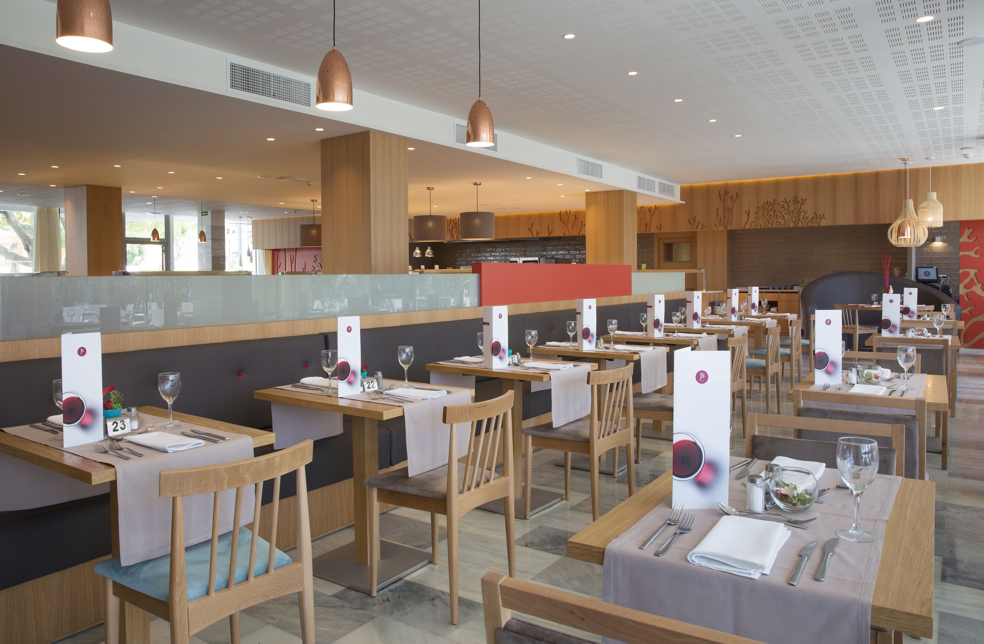 Un restaurant avec des tables et des chaises en bois, un comptoir et des luminaires suspendus.