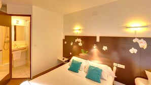 A hotel room with a bed, a nightstand, a bathroom with a sink and mirror, and wall-mounted lights. - The Originals Access, Hôtel Béziers Est (Villeneuve-les-Beziers)