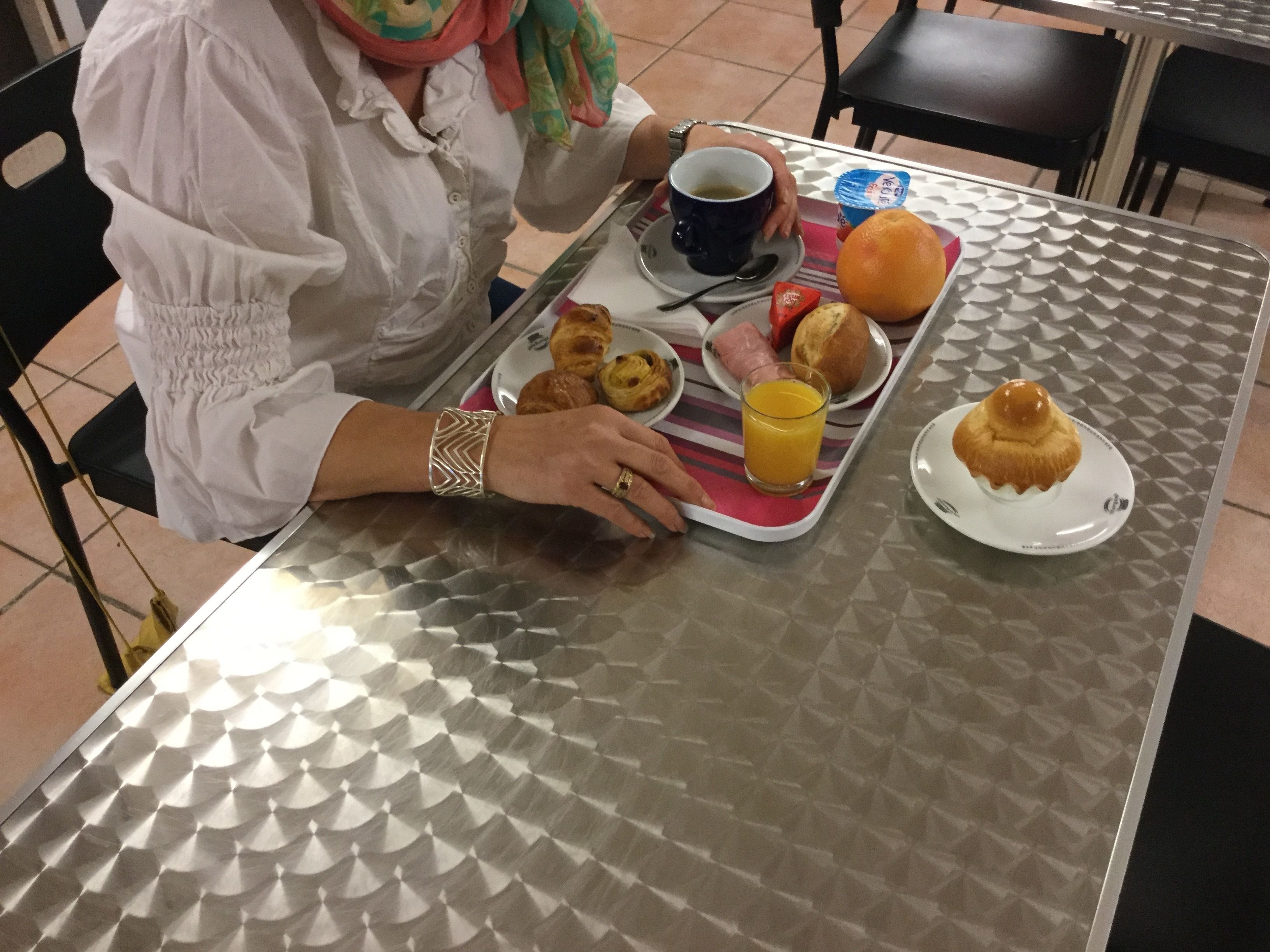 A person seated at a table with a tray containing food items and a cup of coffee.