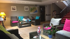 A modern lobby with wicker furniture, a map on the wall, and a staircase. - The Originals Access, Hôtel Béziers Est (Villeneuve-les-Beziers)