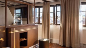 Una habitación con un escritorio de madera, un espejo y vistas de la ciudad a través de amplias ventanas.