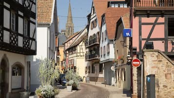 Una estrecha calle adoquinada flanqueada por edificios tradicionales de entramado, con la aguja de una iglesia al fondo y una señal de prohibido el paso.