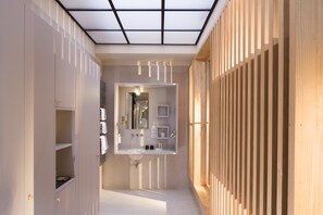 A modern bathroom with a skylight, a large mirror, and a wooden panel wall. - Hôtel Le Colombier (Obernai)