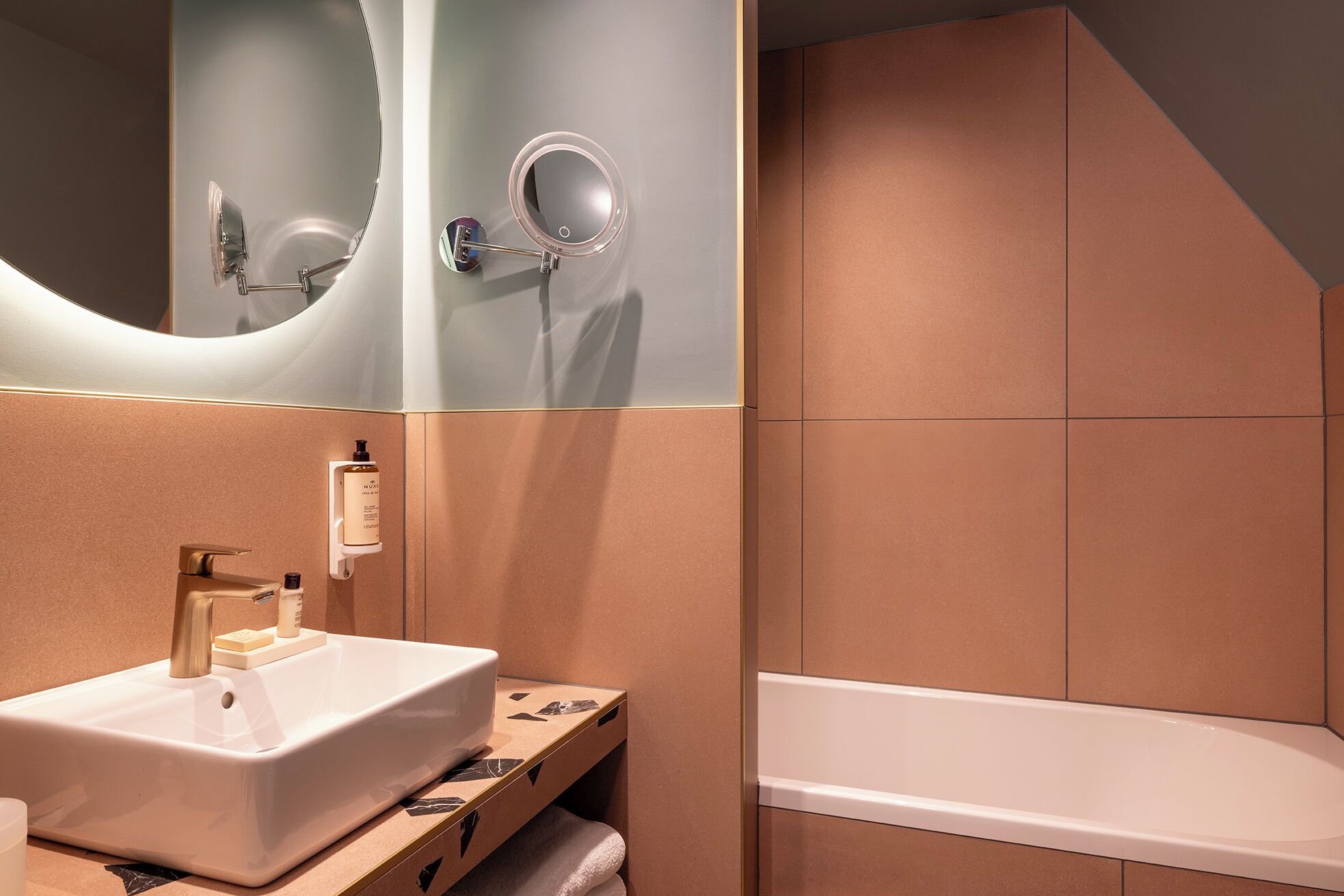 Un baño moderno con un lavamanos blanco, un espejo y una bañera.