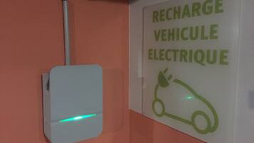 Señal en la pared con el texto 'RECHARGE VEHICULE ELECTRIQUE' y un símbolo de un coche con un enchufe.