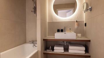 A modern bathroom with a bathtub, a vanity with a mirror, and shelves with towels.