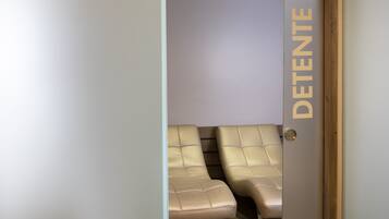 A room with two beige leather chairs and a door with the word "DETENTE" on it.