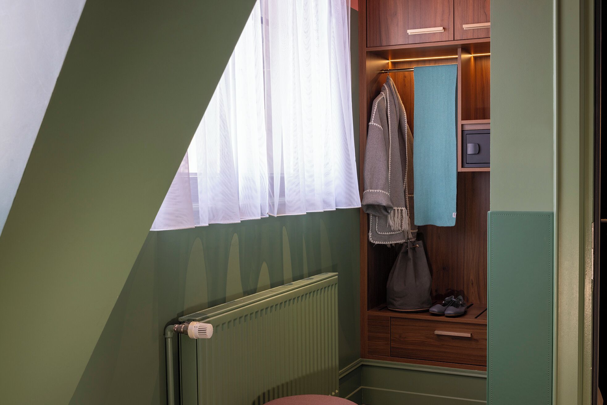 Un baño pequeño y acogedor, con un radiador, un perchero para toallas y un armario de madera.