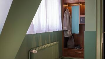 Un baño pequeño y acogedor, con un radiador, un perchero para toallas y un armario de madera.
