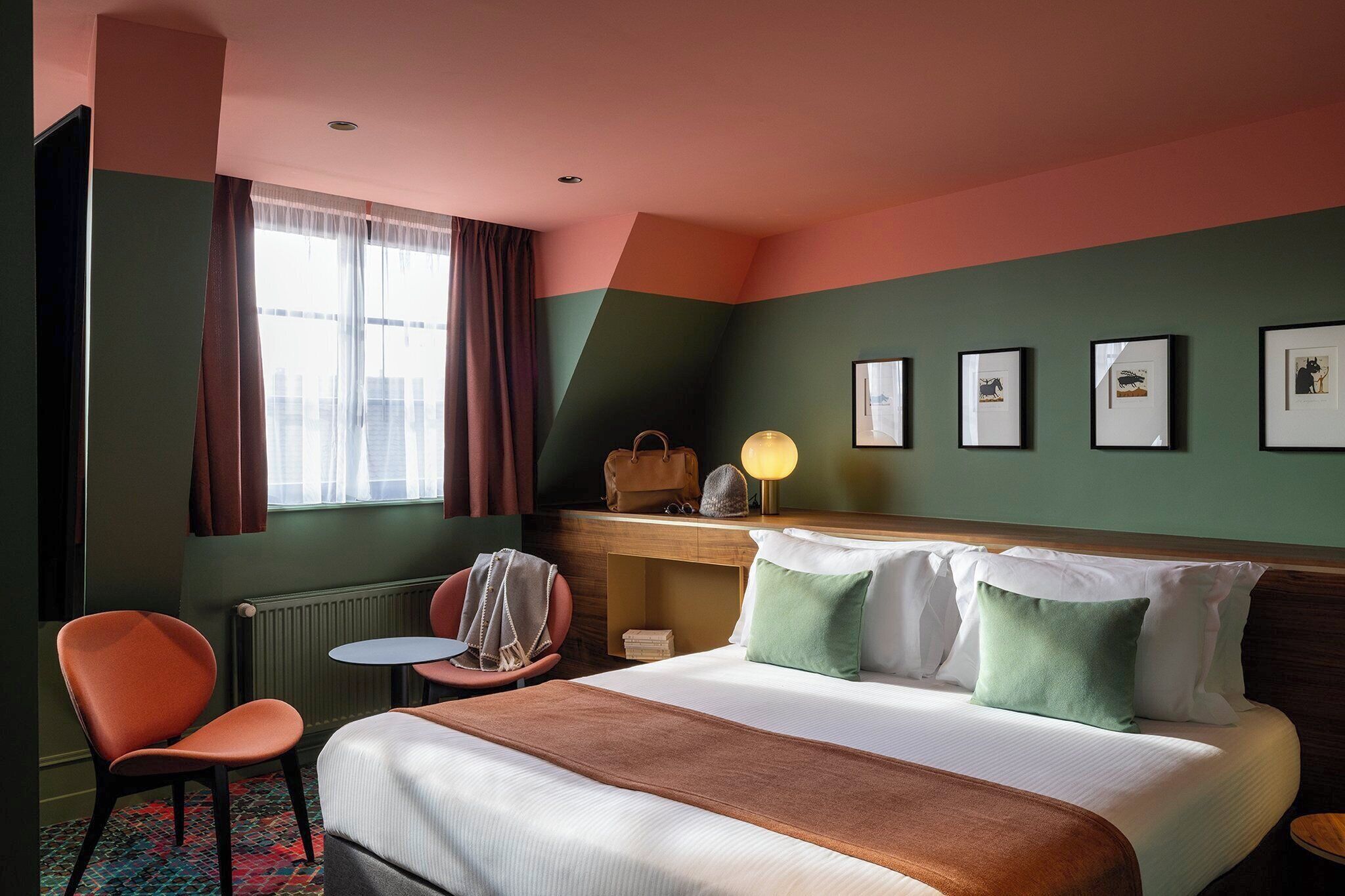 A hotel room with a bed, a desk, a chair, and a window with curtains.