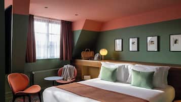 A hotel room with a bed, a desk, a chair, and a window with curtains.