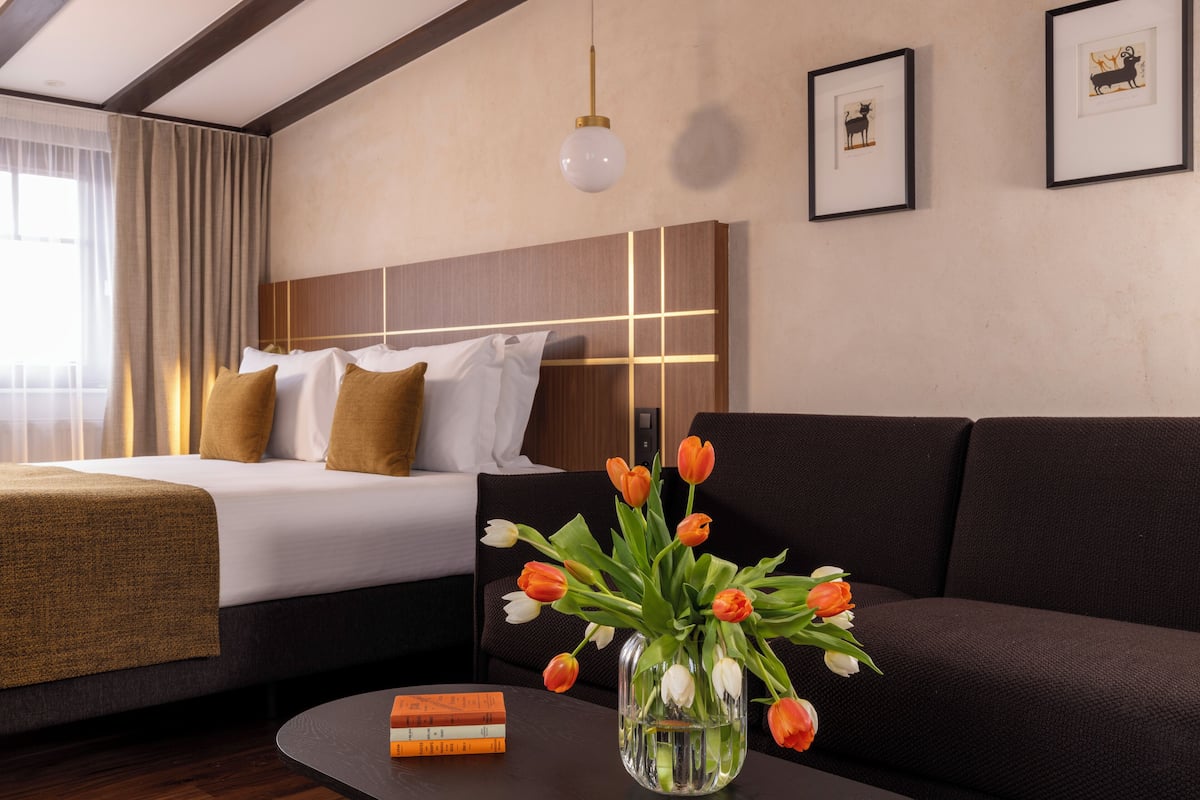 Ein Hotelzimmer mit einem Bett, einem Sofa, einem Couchtisch und einer Tulpenvase.