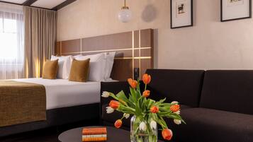 Ein Hotelzimmer mit einem Bett, einem Sofa, einem Couchtisch und einer Tulpenvase.