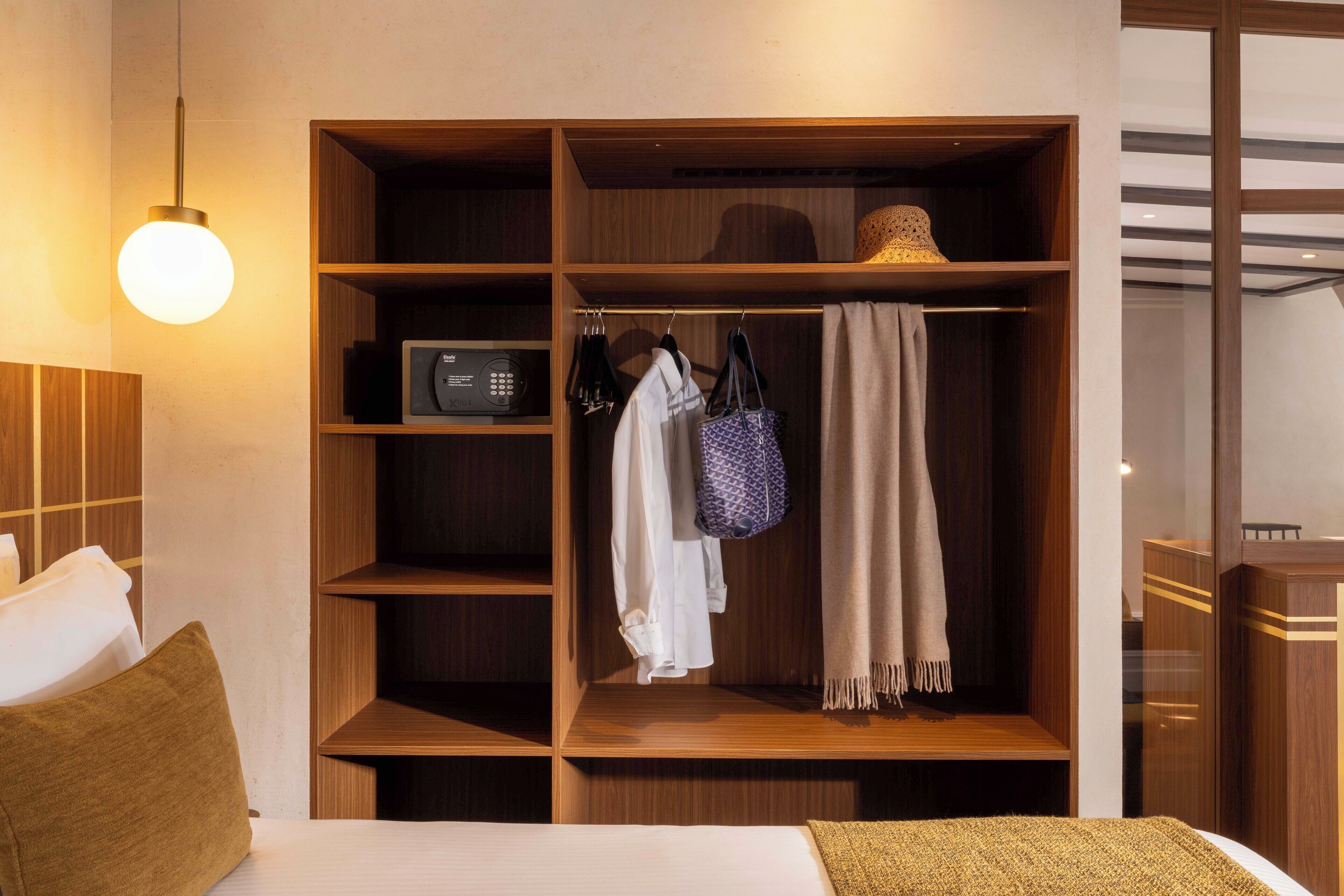 Habitación de hotel con un armario de madera, una cama, una mesita de noche y una lámpara colgante.