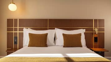 Habitació d'hotel amb un llit gran, dos coixins, una taula de nit i una làmpada fixa a la paret.