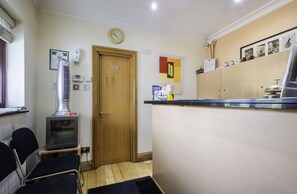 A small kitchen with a microwave, a coffee machine, and a wooden door. - The Brent Hotel  (Harrow)