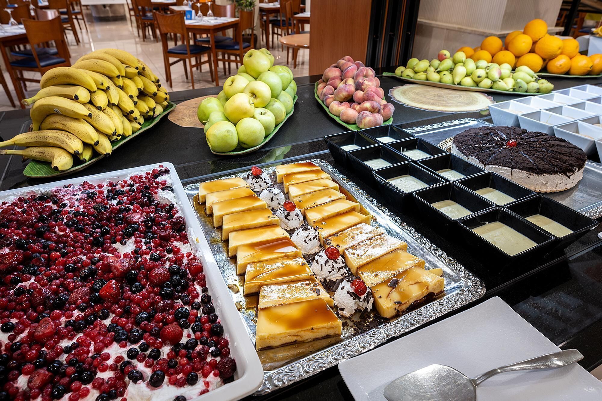 A buffet with various fruits, desserts, and a cake.