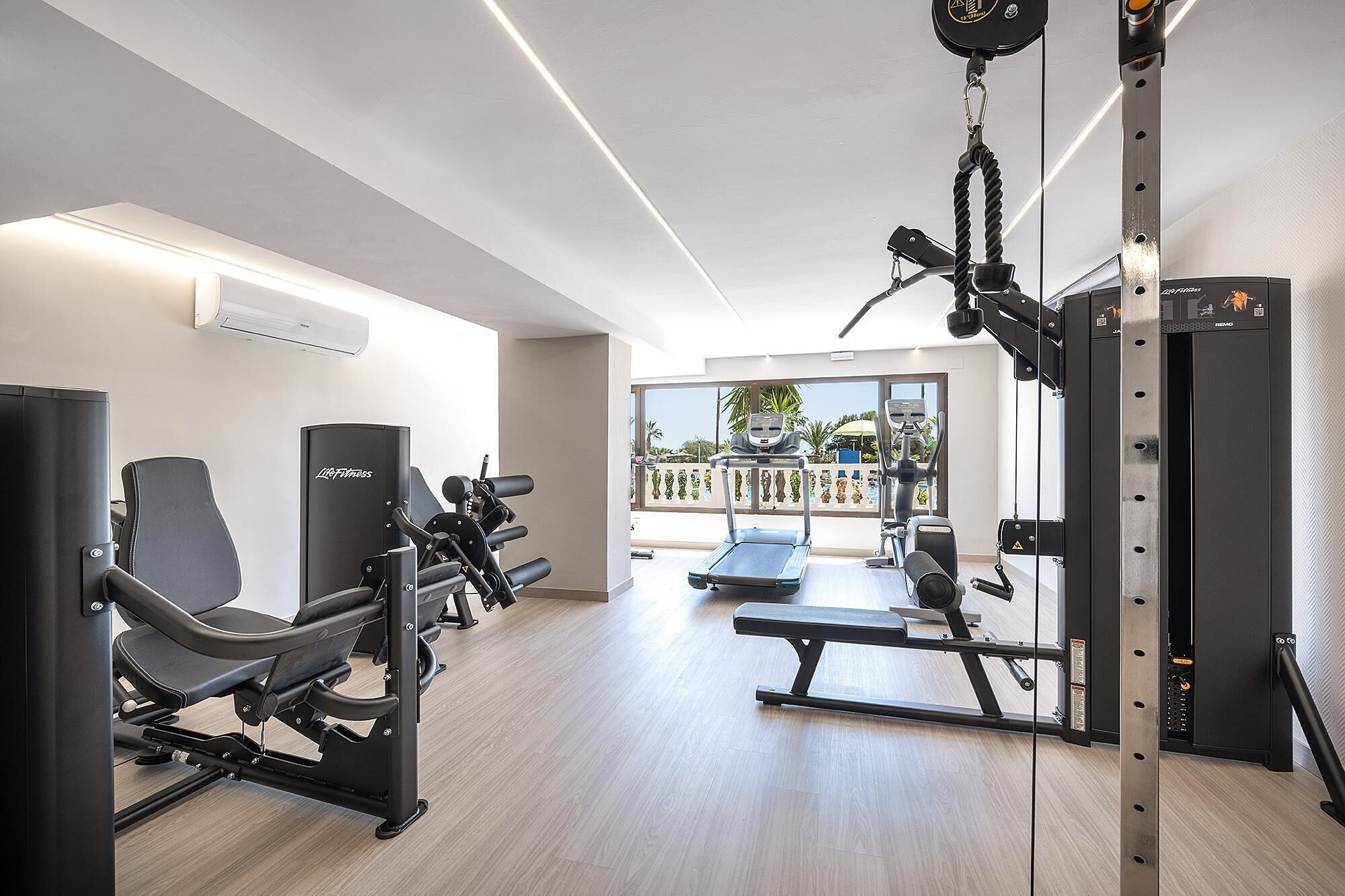 A modern gym with various exercise equipment, including a treadmill, weight machines, and a cable machine.