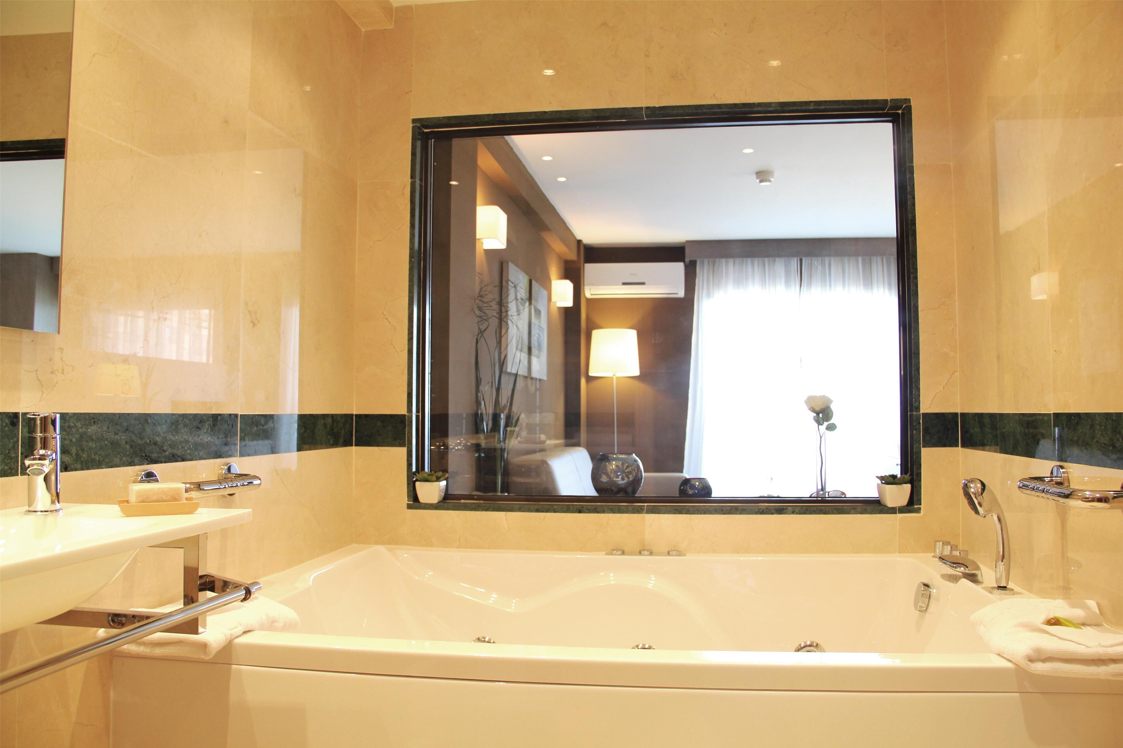 A bathroom with a large mirror, a bathtub, a sink, and a towel rack.