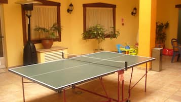 Relax in this inviting space with a ping pong table, potted plants, and a cozy seating area.