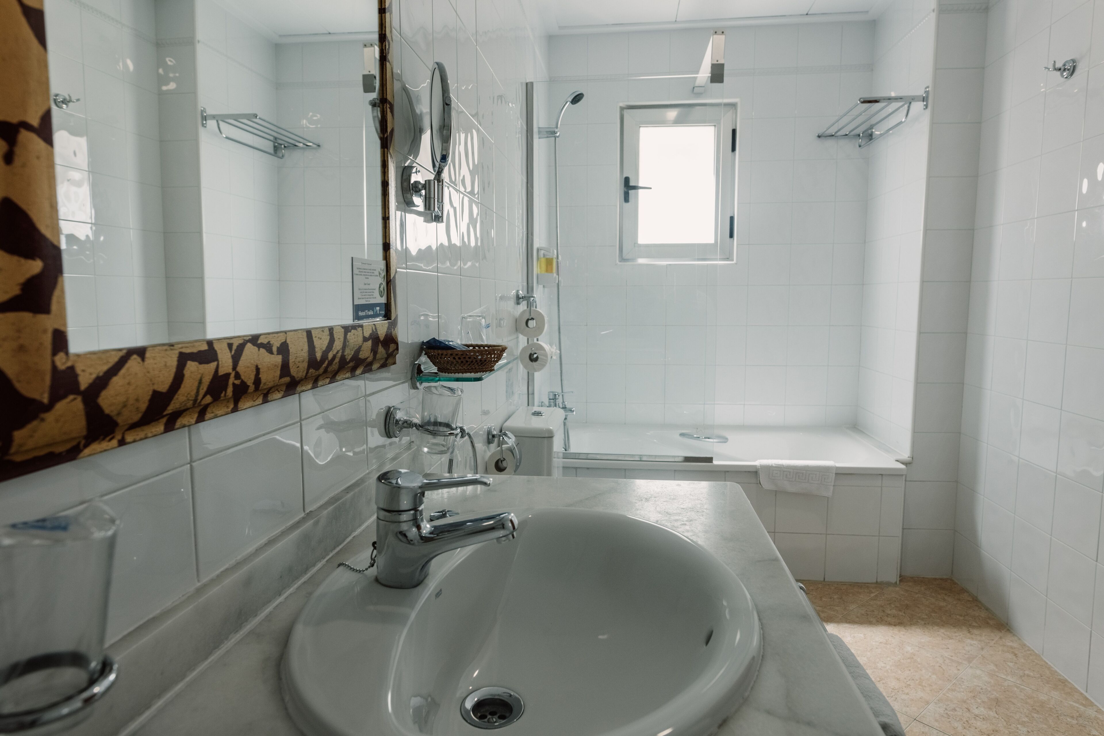 Un baño con lavamanos blanco, espejo, ducha y bañera.