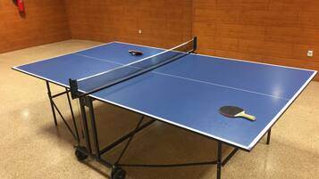 A ping pong table with a fire extinguisher mounted on the wall.