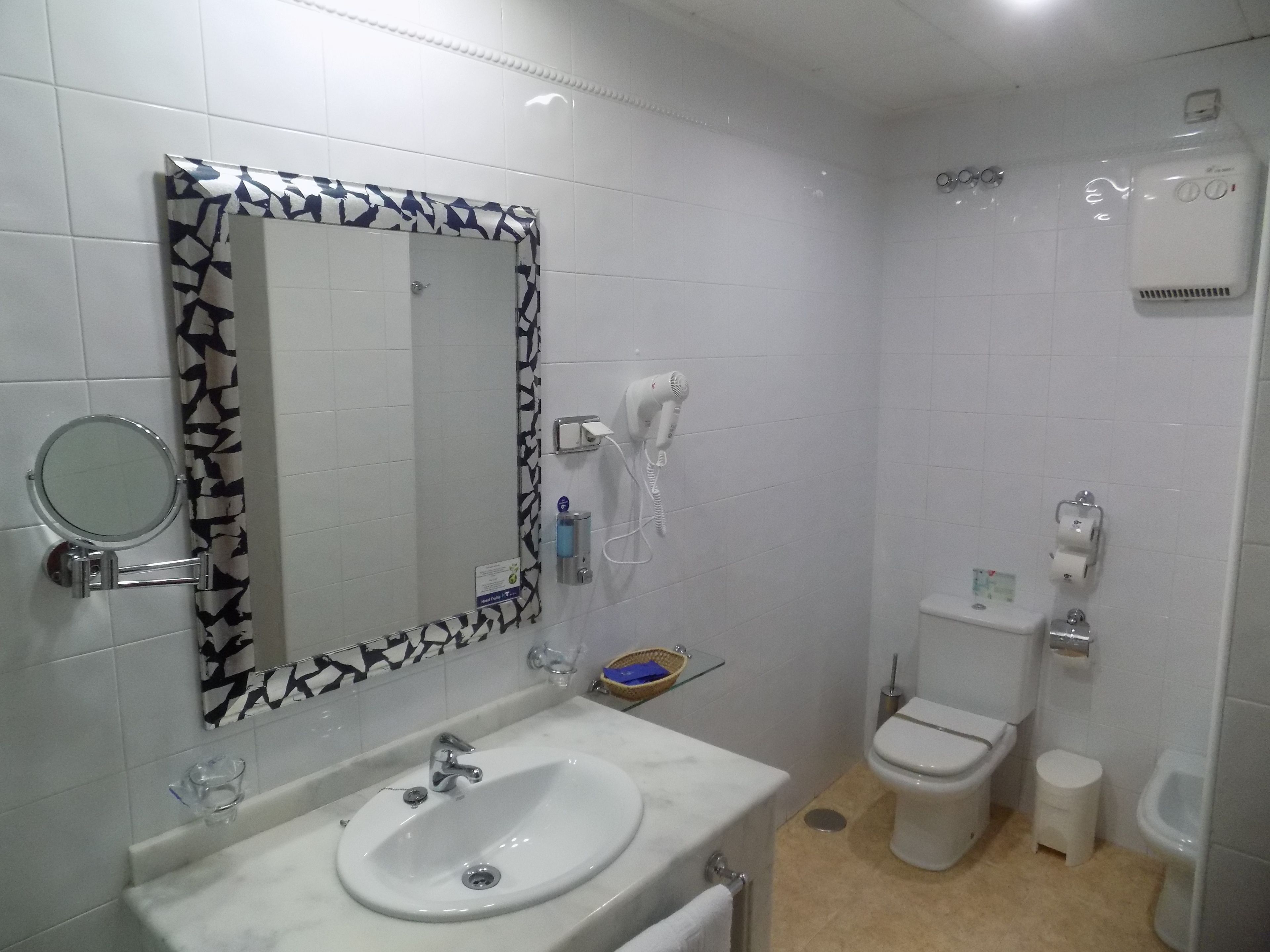 A bathroom with a white sink, a mirror with a black and white frame, a toilet, and a bidet.
