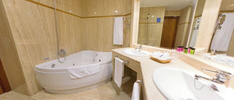 A modern bathroom with a bathtub, two sinks, a large mirror, and a shower.