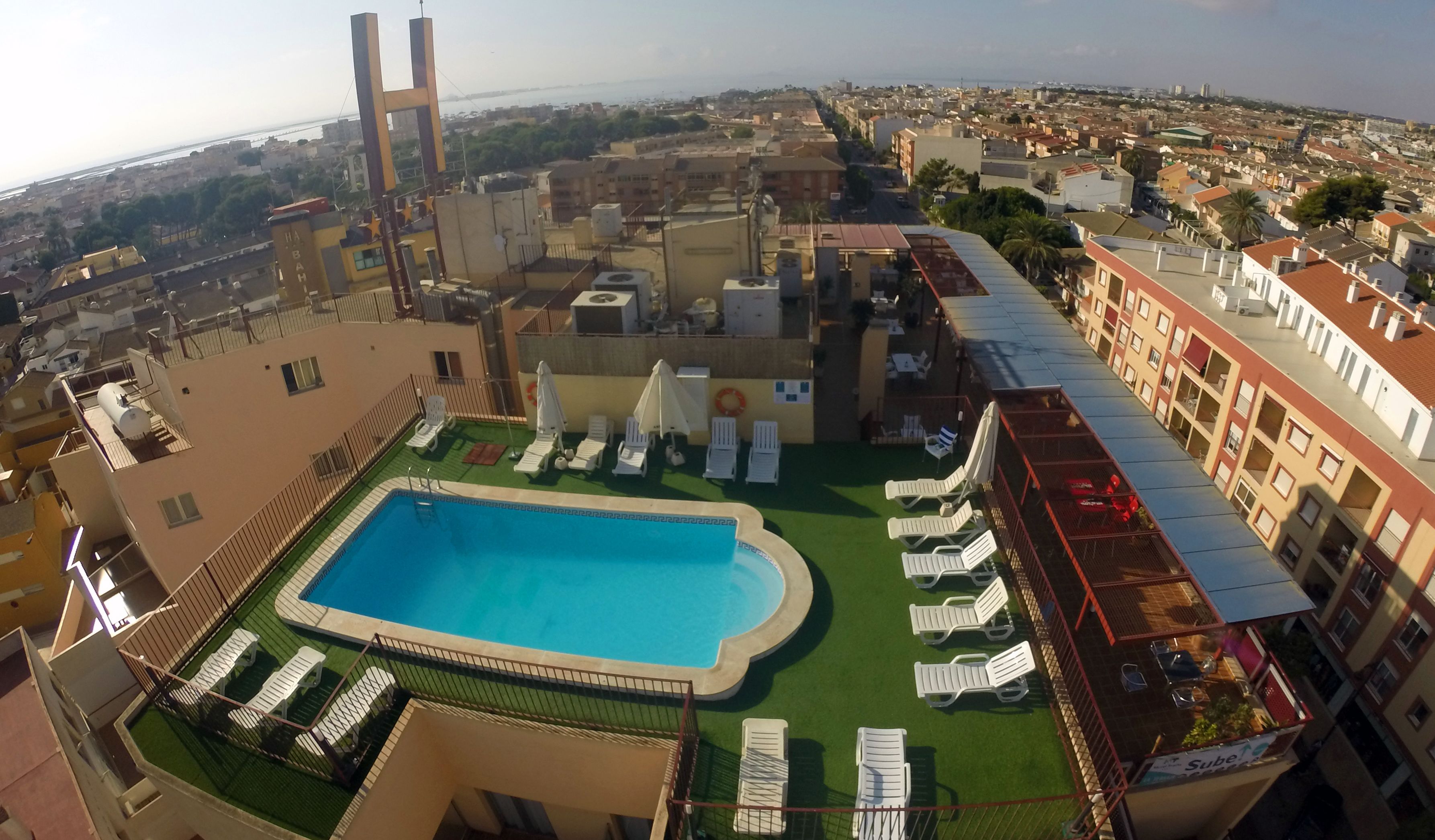 A rooftop pool with lounge chairs and a view of the cityscape.