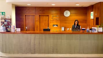 Un mostrador de recepción de hotel con detalles de madera, un reloj y un letrero que dice 'Hotel Train'.