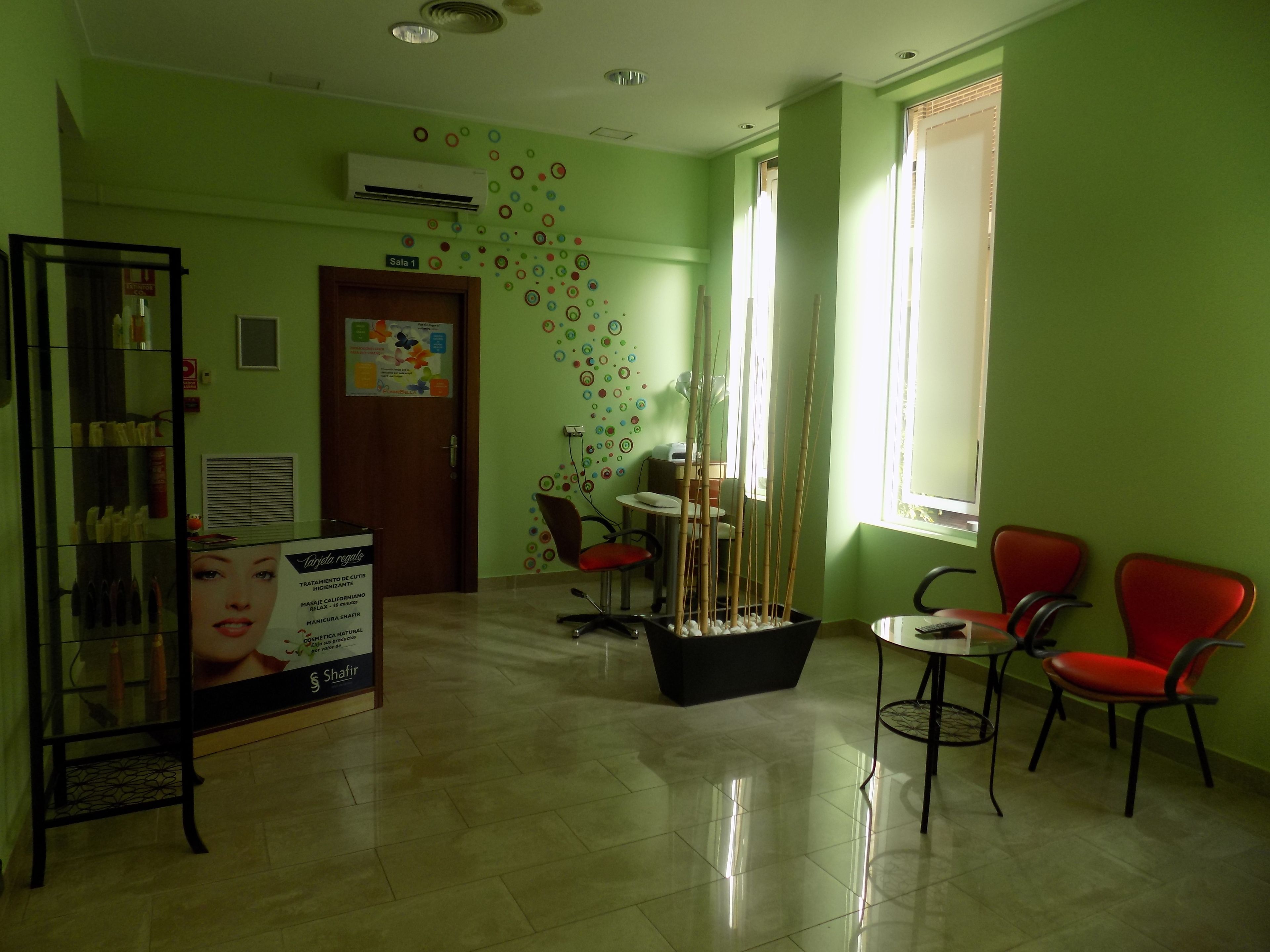 A reception area with a glass display case, a signboard, a reception desk, and a seating area with chairs.