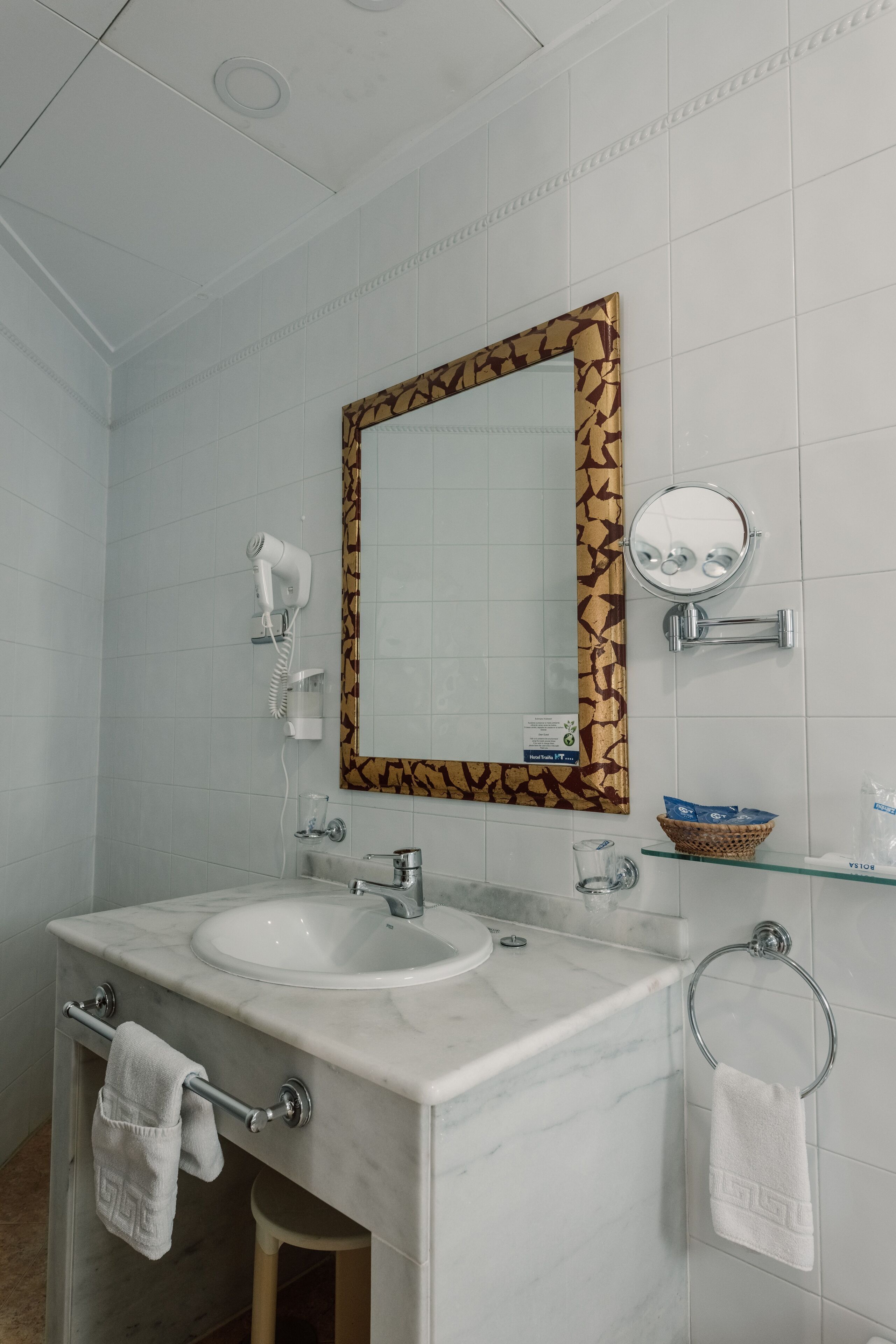 A bathroom with a white sink, mirror, and towel rack.