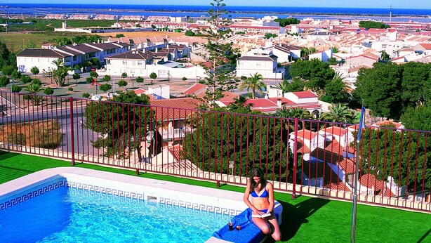 A pool area with a view of a residential area and the sea. - Hotel Traíña (San Pedro del Pinatar)