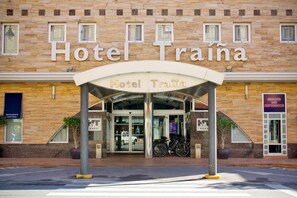 A hotel entrance with a stone facade, a covered entrance, and a sign that reads "Hotel Traína". - Hotel Traíña (San Pedro del Pinatar)