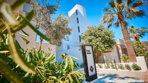 A modern building with a sign reading "Prokur Alakaja" surrounded by palm trees and greenery. - Protur Atalaya Apartamentos (Son Servera)