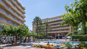 Una piscina al aire libre, sombrillas, sillones reclinables de piscina