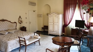 Una habitación de hotel con una cama, un armario, un escritorio con silla, un televisor y una lámpara.