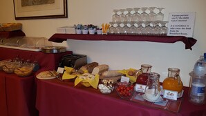 Una mesa de buffet con diversos alimentos y bebidas, incluyendo pan, pasteles y una variedad de jugos.