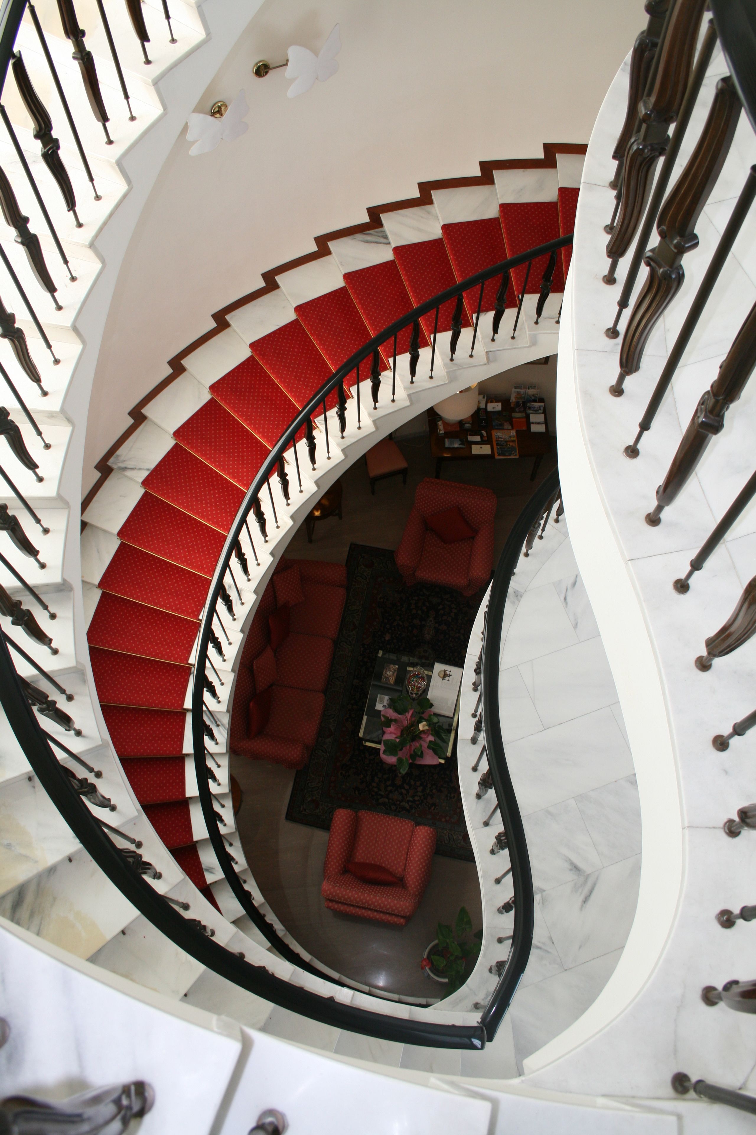 A spiral staircase with red steps leading to a living area with a red sofa and a coffee table.