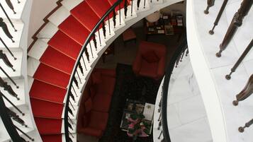 A spiral staircase with red steps leading to a living area with a red sofa and a coffee table.