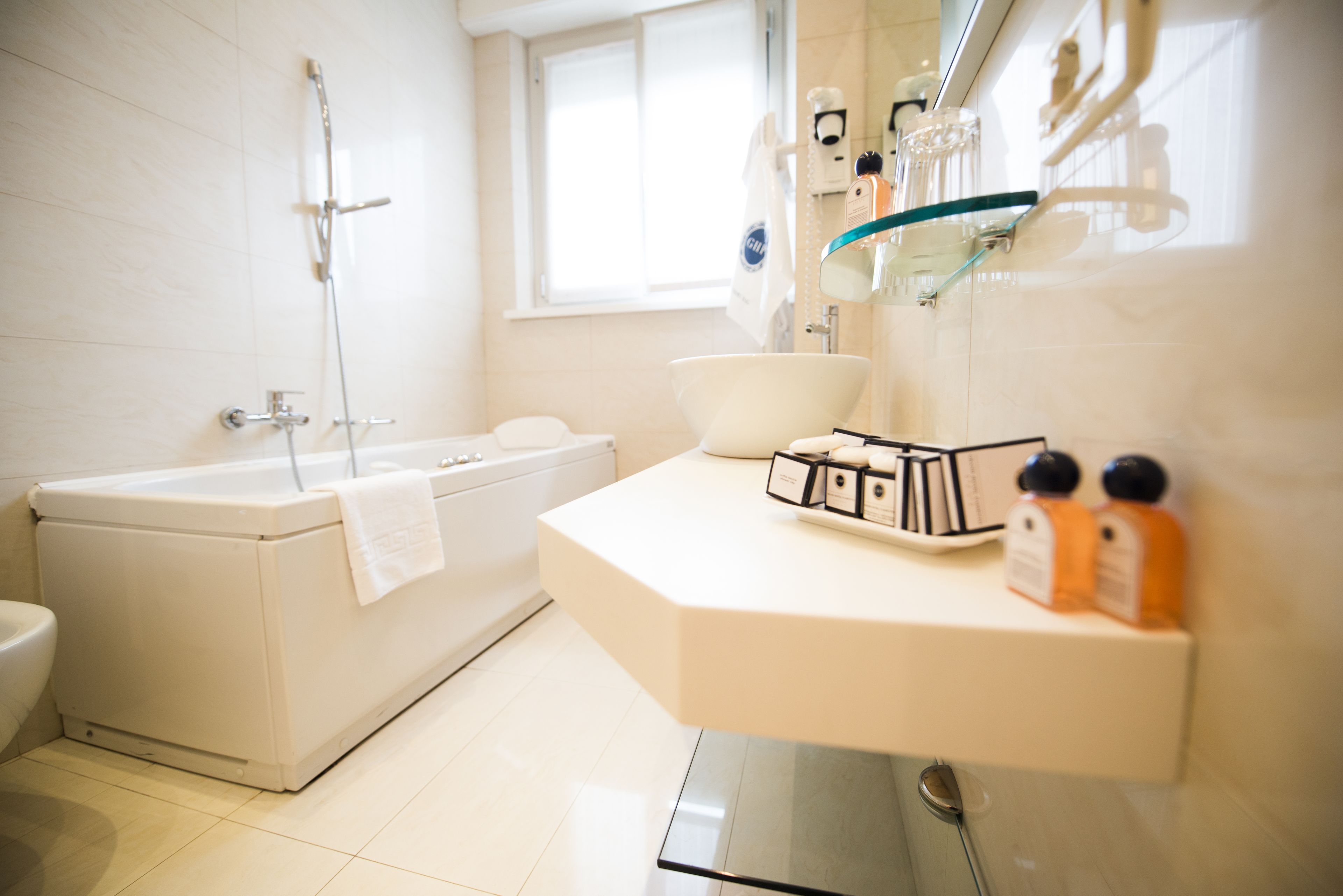 A modern bathroom with a bathtub, a sink with toiletries, and a toilet.