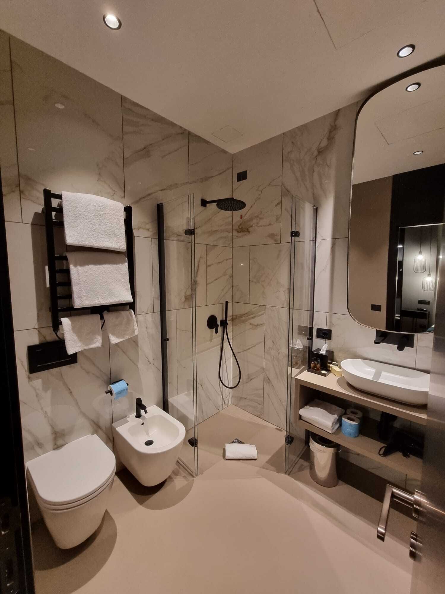 A modern bathroom with a toilet, bidet, and a glass-enclosed shower area.