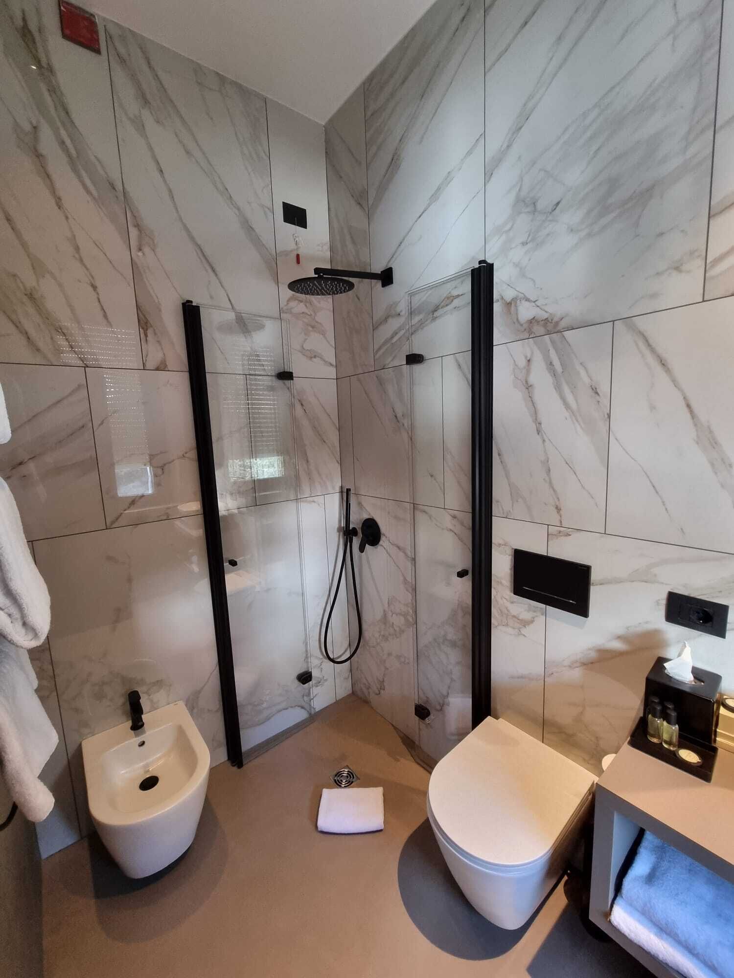 Een moderne badkamer met een inloopdouche, een bidet, een toilet en een wastafel met spiegel.
