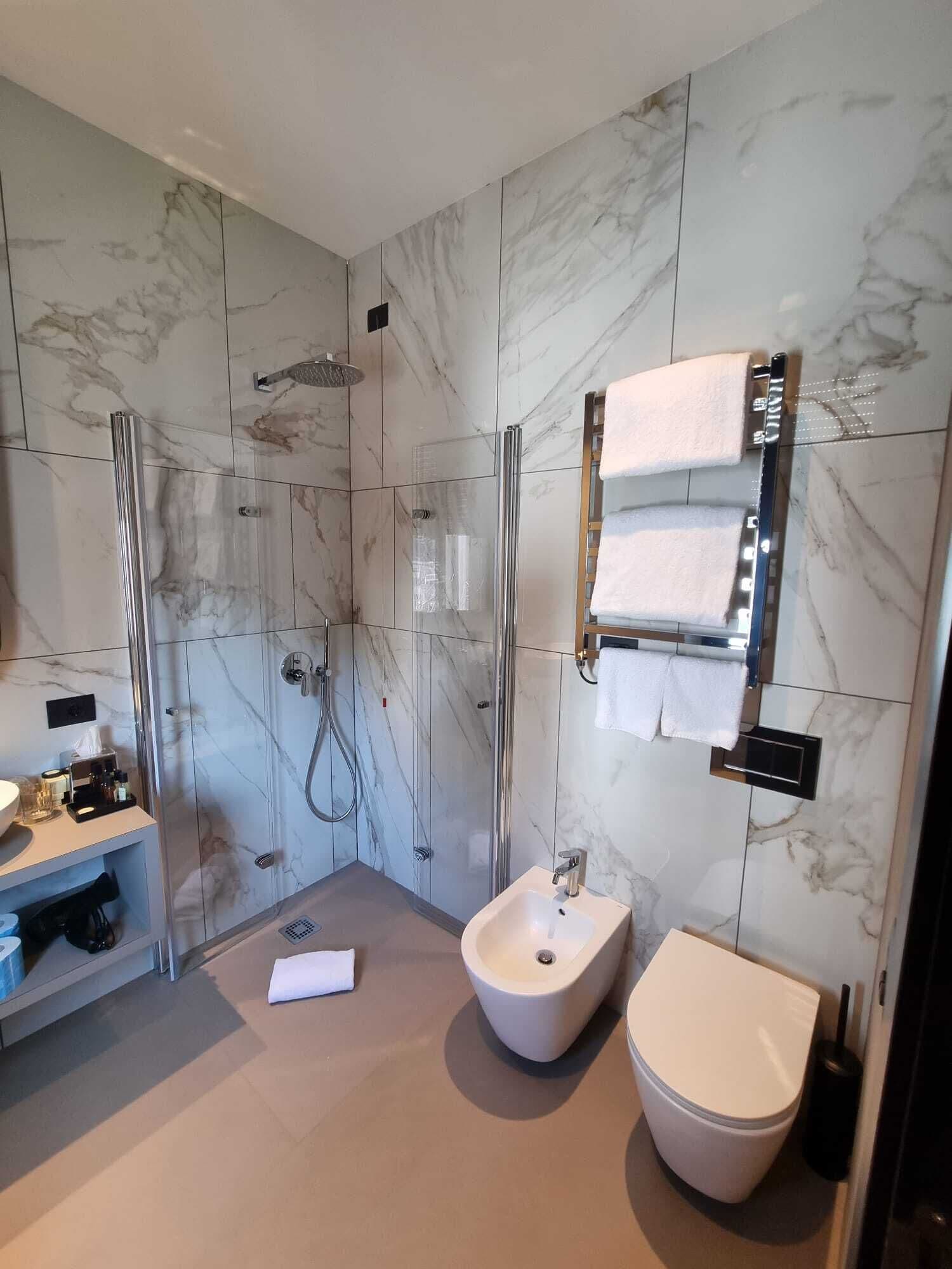 Ein modernes Badezimmer mit einer Duschkabine aus Glas, einem Standwaschbecken und einer Toilette.