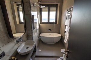 Un baño moderno con una bañera independiente, un lavamanos y un espejo grande.