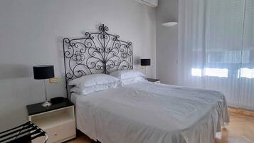 A modern bedroom with a large bed, a nightstand, a lamp, and a chair.