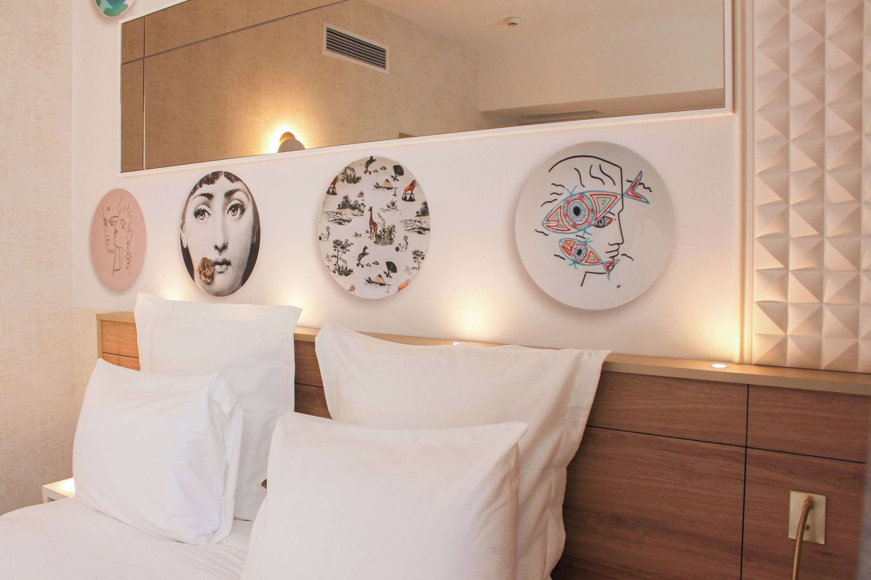 Une chambre à coucher avec un lit, des oreillers blancs et trois œuvres d’art murales de forme circulaire.