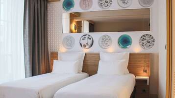 Habitación de hotel con dos camas, un espejo grande y obras de arte colgadas en la pared.