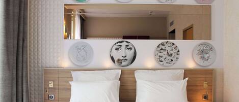 A hotel room with a large bed, a wooden headboard, a mirror, and artwork on the walls.
