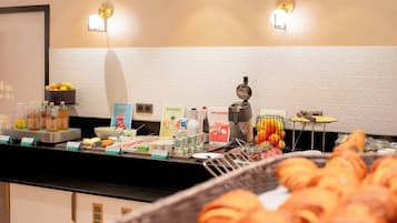 A breakfast buffet with various food items and beverages, including croissants and a coffee machine.